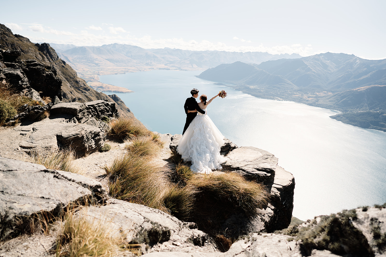 Queenstown Wedding Photographer 結婚式 couple standing on top of a cliff overlooking lake wanaka in クイーンズタウン, ニュージーランド.